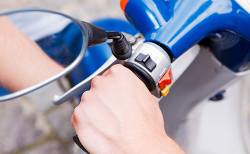Main gauche sur un guidon de scooter de couleur bleue